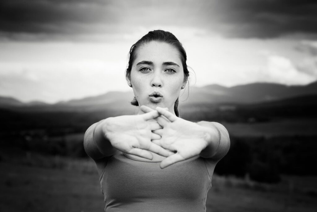 Junge Frau beim bewussten Ausatmen mit gefalteten Händen vor der Brust – Symbolbild für Atemübungen zur Beruhigung bei Redeangst
