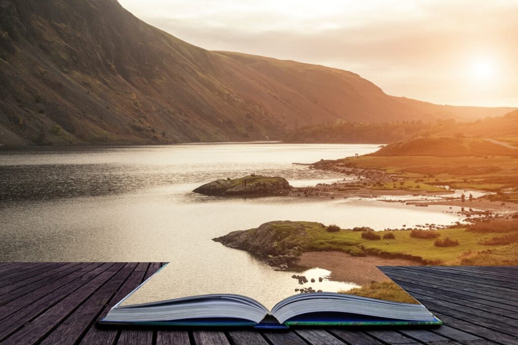 Ein aufgeschlagenes Buch liegt auf einem Holztisch und verschmilzt optisch mit einer idyllischen Landschaft aus Bergen, Wasser und Sonnenuntergang – Symbolbild für die Magie des Storytellings und das Eintauchen in neue Welten.