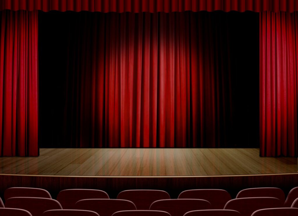 Rote Vorhänge auf einer leeren Bühne in einem Theater – symbolisiert den Aufbau einer Präsentation nach der klassischen 3-Akt-Struktur mit Anfang, Konflikt und Auflösung.